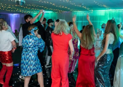 Colourfully dressed guests dancing at a 60th birthday disco in Amersham