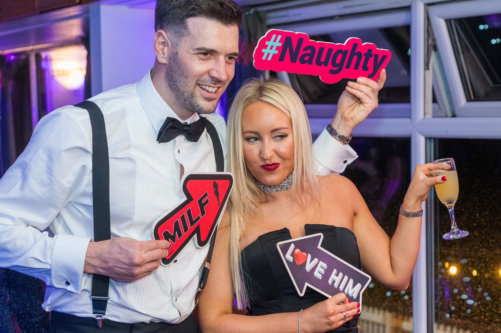 Couple posing with photo booth props at a party