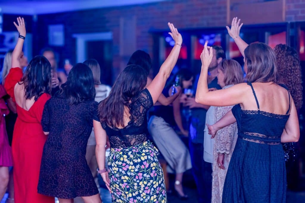 Guests with their hands up on the dance floor at Leona’s 40th