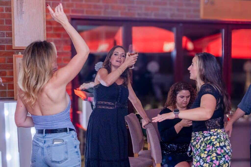 Guests dancing in front of the clubhouse windows as the sun sets over the Chilterns