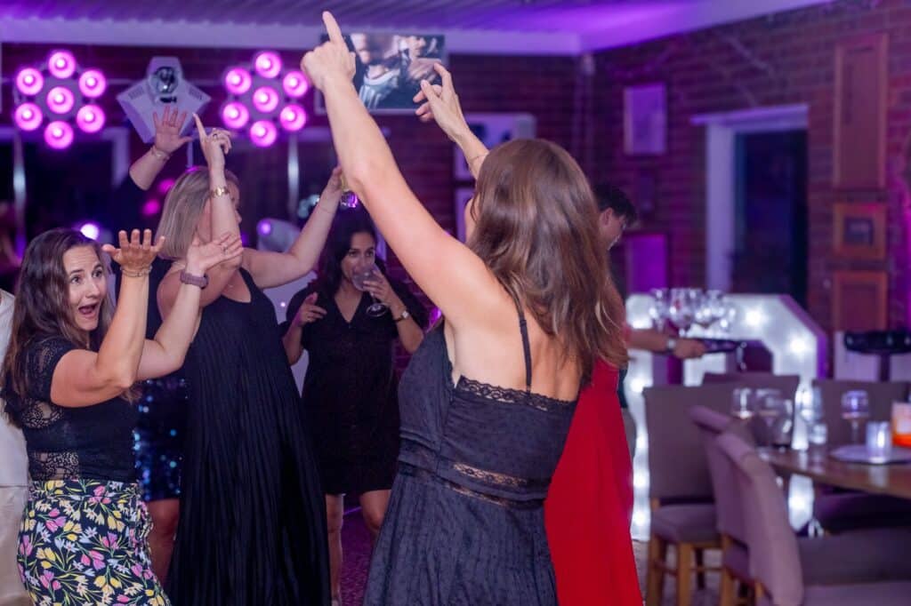 Friends dancing together under the party lights at Leona’s 40th
